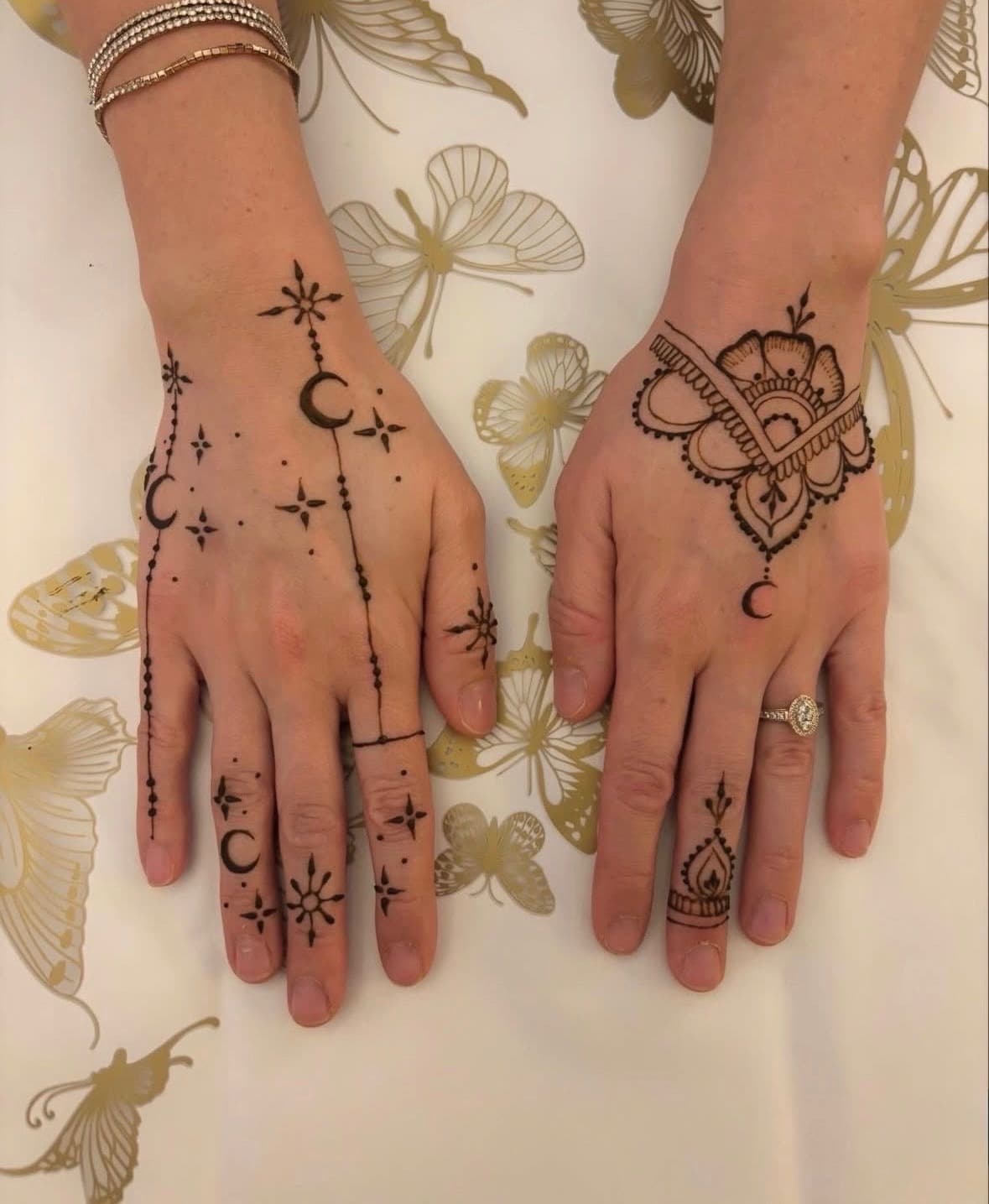 Two hands side by side with celestial moons and stars in jagua, opposite hand with mandala